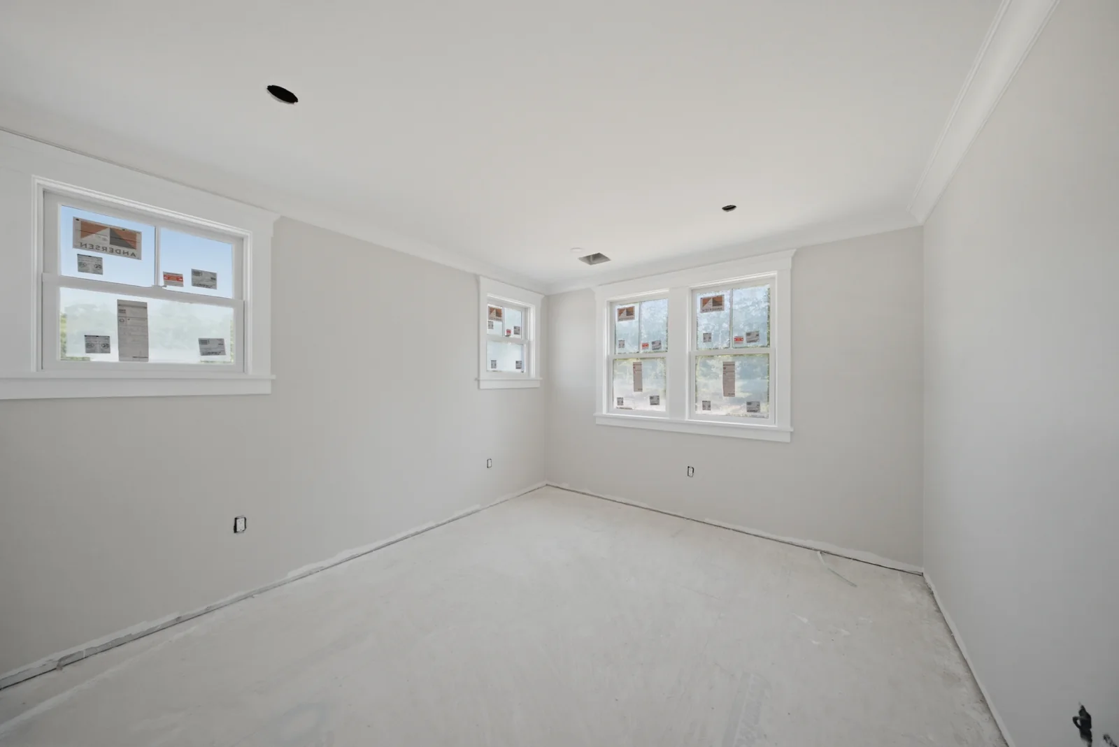 Interior finish work on the South Shore: crown moulding and window casing installed, with the windows still stickered and the floor bare