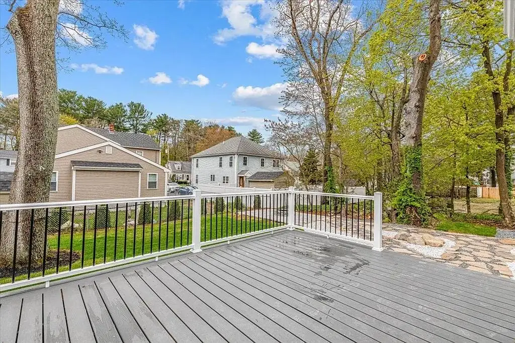 Deck builder on the South Shore: a composite deck with a black metal railing and a stone patio beside it