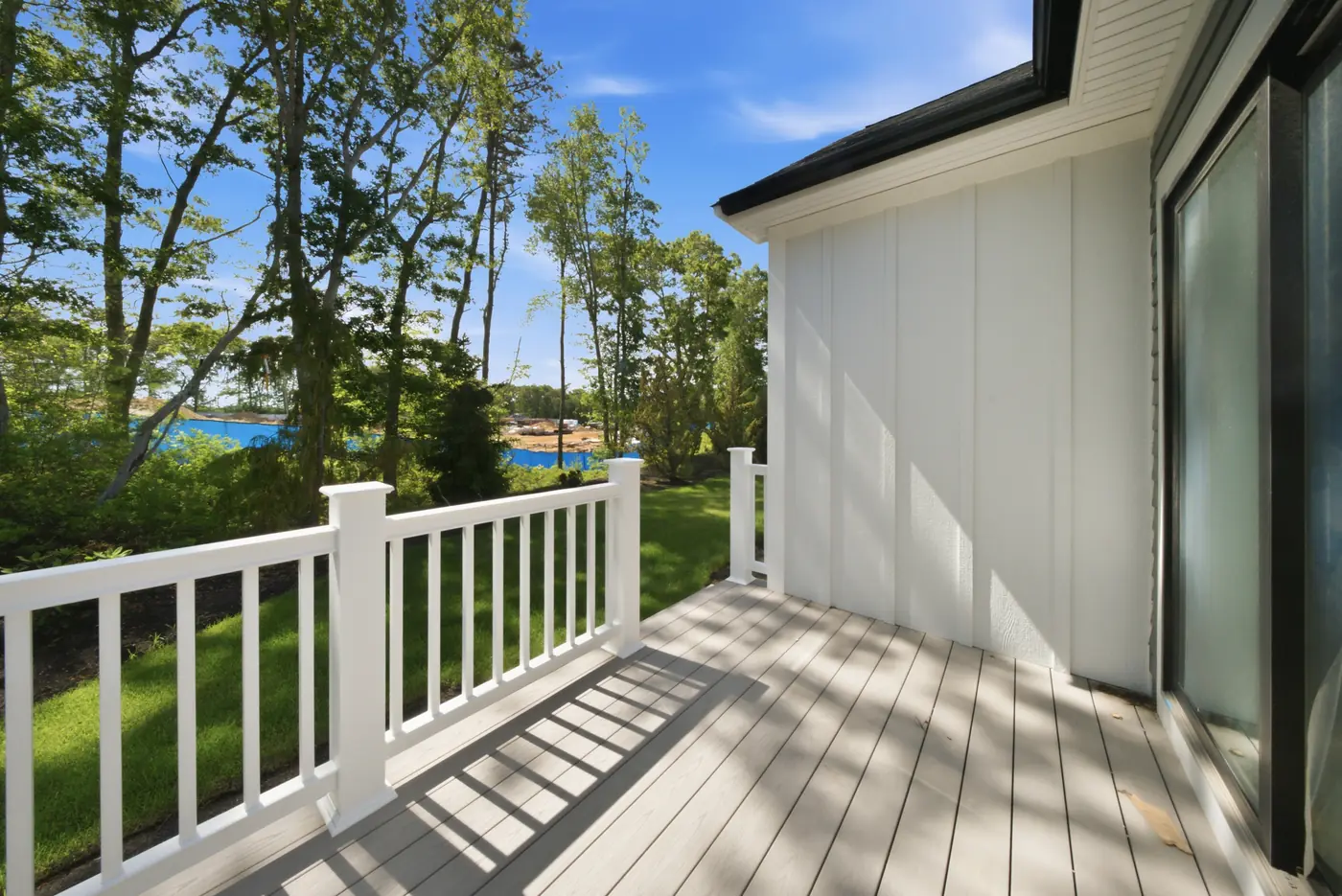 A deck built on the South Shore with a white railing, looking out over the trees toward the water