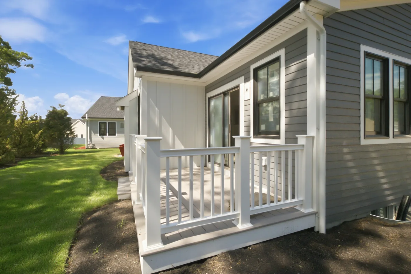 A porch railing and deck boards finished, with the lawn graded up to it